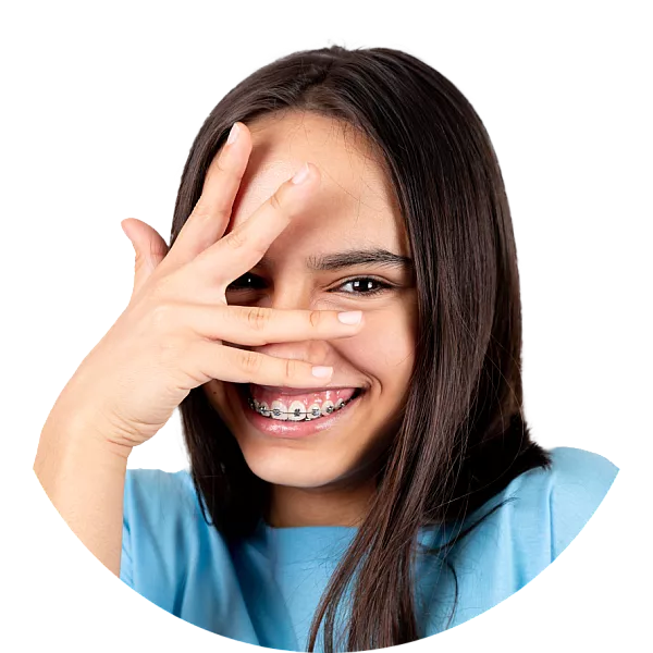 brunette teenage girl with big smile and braces hiding, looking through hands