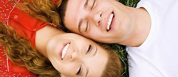 young adult teenagers laying on grass side by side, laughing and smiling with invisalign